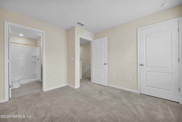 unfurnished bedroom featuring ensuite bath and light tile floors