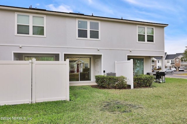 rear view of house featuring a lawn and central AC unit