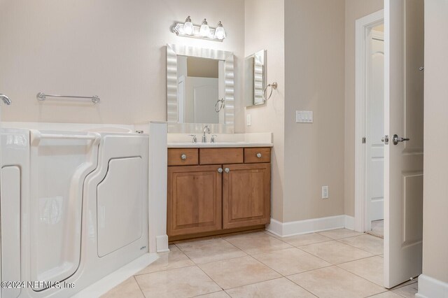 bathroom featuring tile patterned flooring, vanity, and washer / dryer