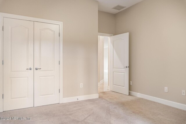 unfurnished bedroom featuring light colored carpet and a closet