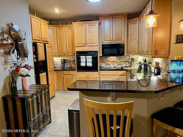 kitchen featuring pendant lighting, light tile floors, backsplash, a breakfast bar area, and black appliances