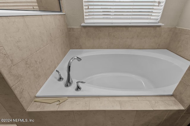 bathroom with tiled tub and a healthy amount of sunlight