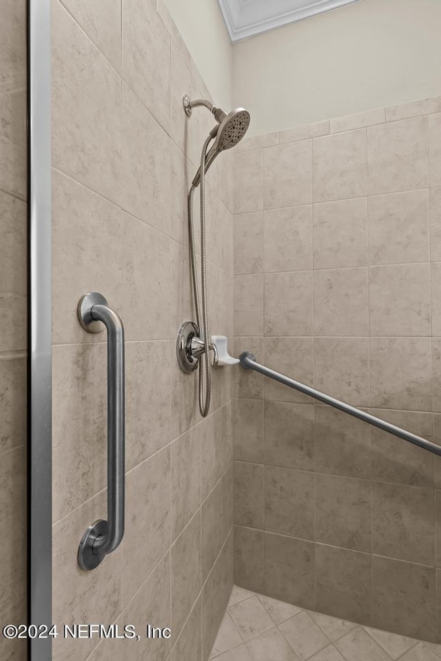 bathroom with ornamental molding and a tile shower