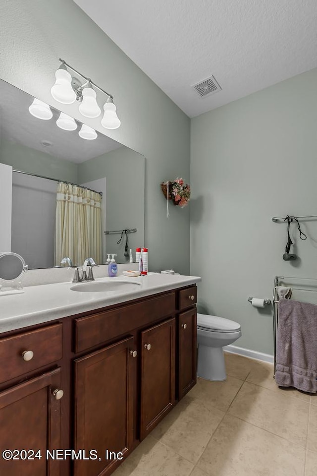 bathroom featuring toilet, a textured ceiling, vanity with extensive cabinet space, and tile flooring