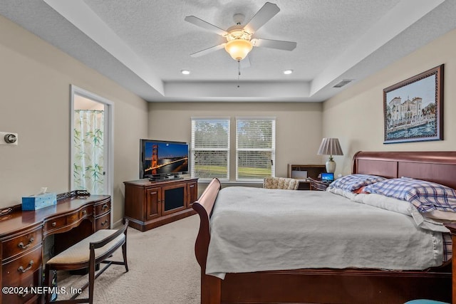 carpeted bedroom with a raised ceiling, ceiling fan, and a textured ceiling