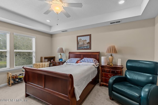 carpeted bedroom with a raised ceiling and ceiling fan