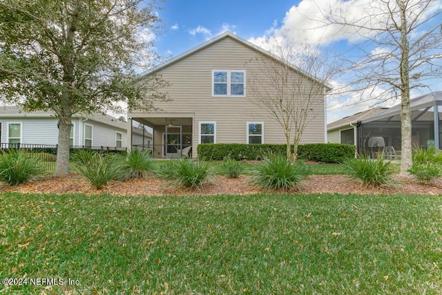 rear view of property with a yard and glass enclosure