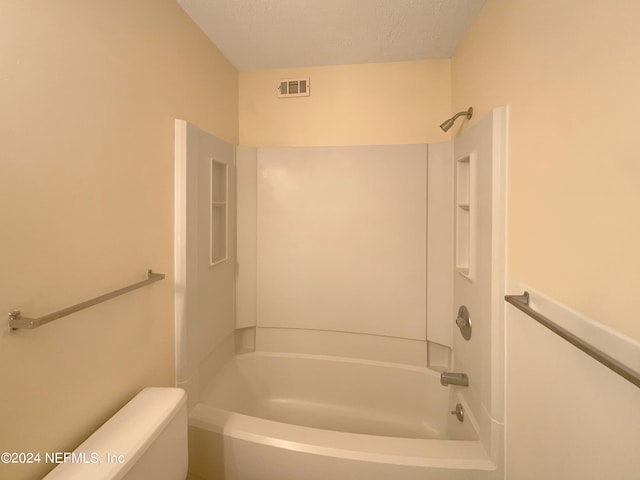 bathroom featuring toilet, washtub / shower combination, and a textured ceiling