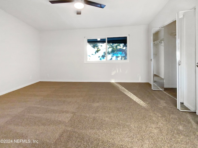 unfurnished bedroom with a closet, dark carpet, and ceiling fan