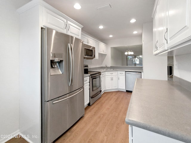 kitchen with hanging light fixtures, appliances with stainless steel finishes, light hardwood / wood-style floors, white cabinets, and a chandelier