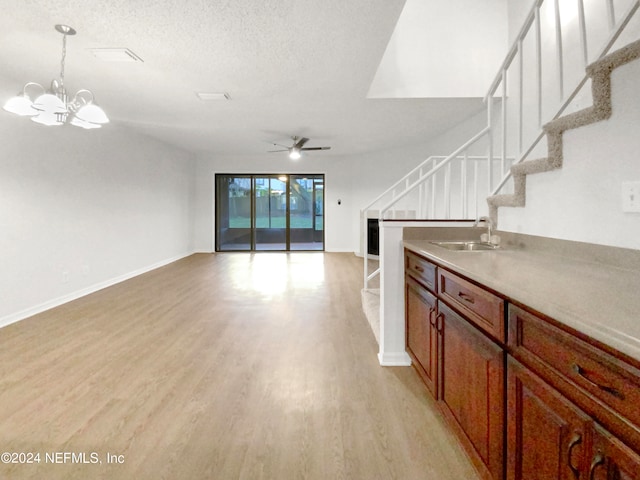 interior space featuring a textured ceiling, ceiling fan with notable chandelier, sink, and light wood-type flooring