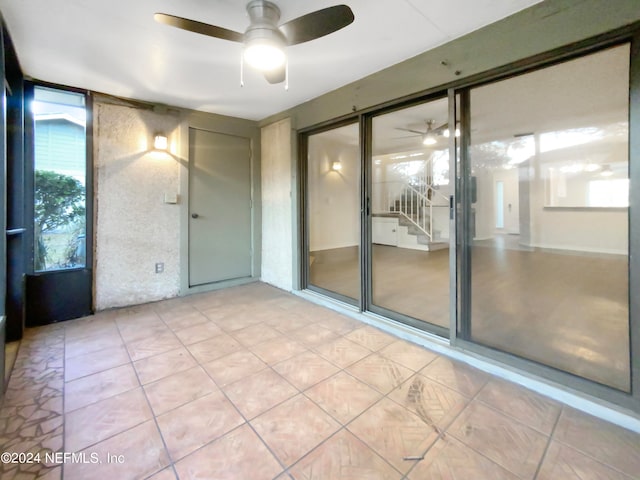 tiled empty room featuring ceiling fan