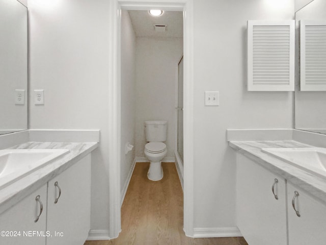 bathroom with toilet, vanity with extensive cabinet space, and hardwood / wood-style flooring