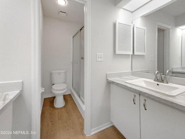 bathroom with toilet, vanity, an enclosed shower, and hardwood / wood-style flooring