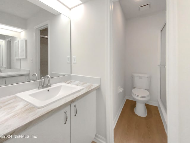 bathroom with toilet, vanity, and wood-type flooring