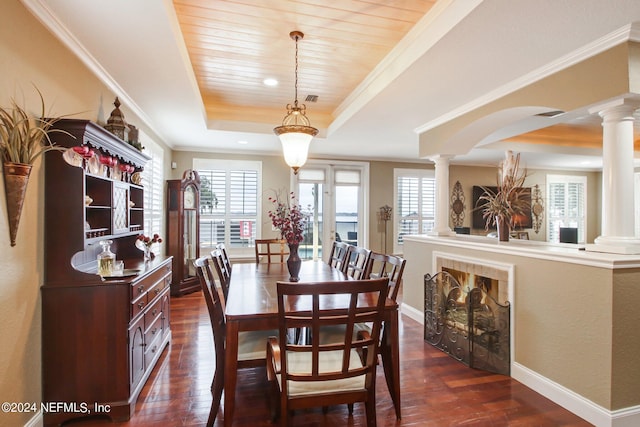 dining area with a tray ceiling, dark hardwood / wood-style floors, wooden ceiling, and decorative columns