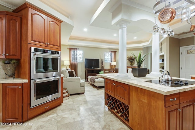 kitchen featuring open floor plan, double oven, a raised ceiling, and ornate columns