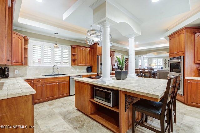 kitchen featuring decorative backsplash, decorative columns, stainless steel appliances, a raised ceiling, and sink