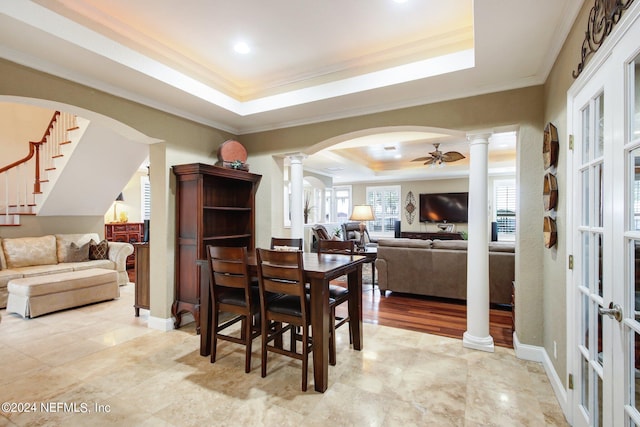 dining area featuring crown molding, a raised ceiling, and ornate columns