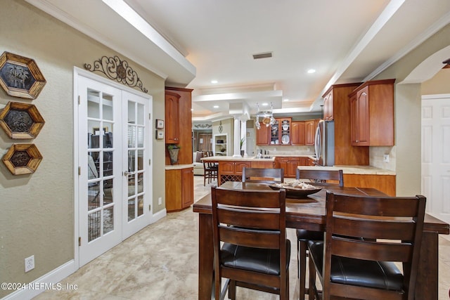 dining room with recessed lighting, ornamental molding, a raised ceiling, and french doors