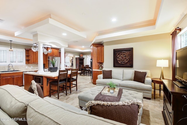 living room featuring decorative columns, a raised ceiling, crown molding, and recessed lighting