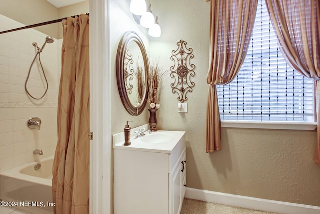 bathroom with a textured wall, shower / tub combo with curtain, vanity, and baseboards