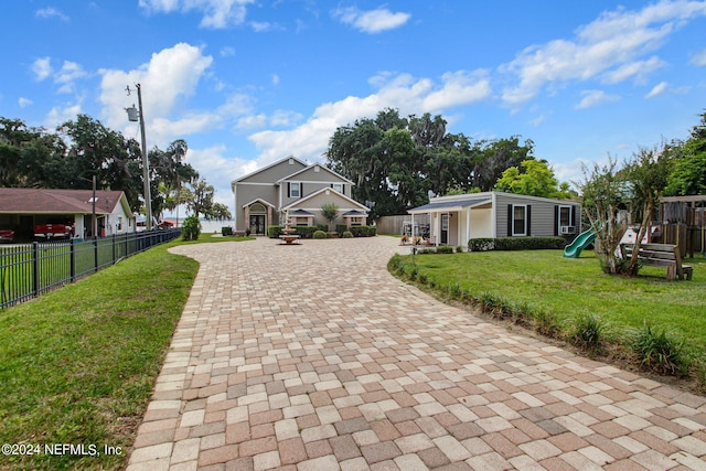 exterior space with a front yard, decorative driveway, a playground, and fence