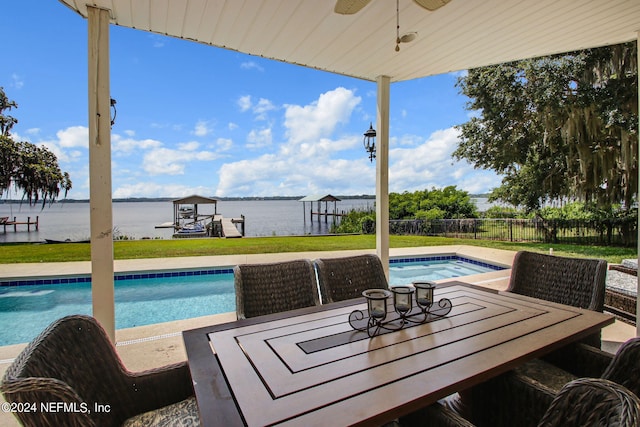 view of pool with a water view, ceiling fan, and a lawn