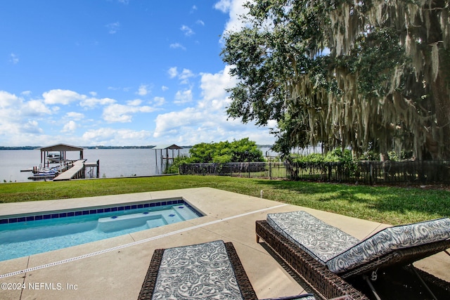 view of swimming pool with a dock, a yard, a water view, and a patio