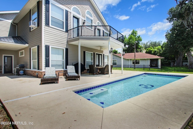 rear view of property with a fenced in pool, a patio, a balcony, fence, and brick siding