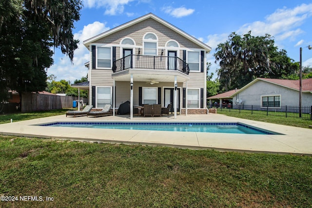 back of house featuring a yard, outdoor lounge area, ceiling fan, and a balcony