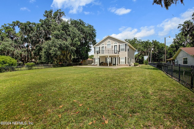 rear view of house featuring a balcony and a yard