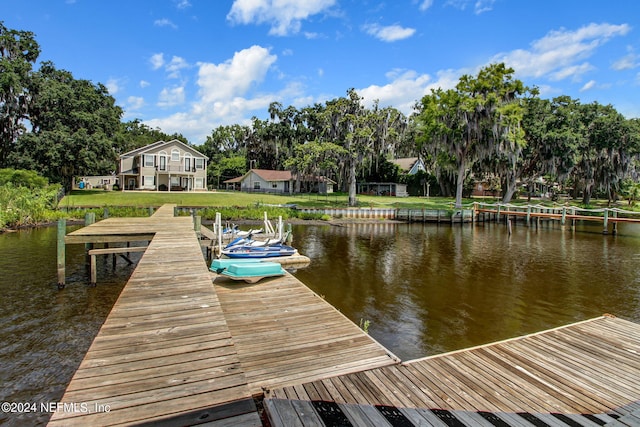 view of dock featuring a lawn and a water view