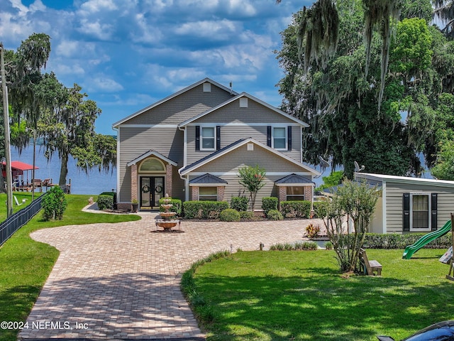 view of front facade with french doors, fence, and a front lawn