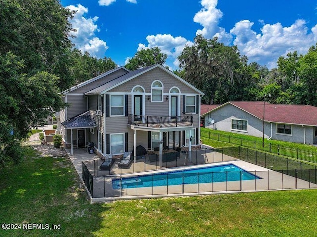 back of property featuring a fenced in pool, a yard, a patio area, fence, and a balcony