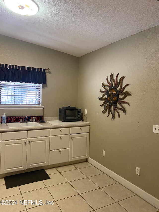 interior space with white cabinets, a textured ceiling, and sink