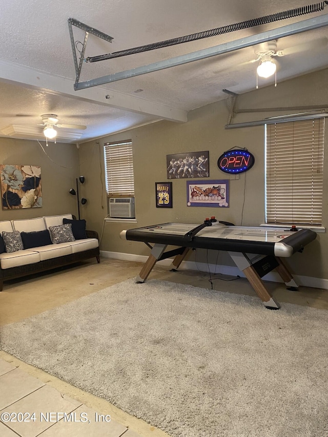 game room featuring a textured ceiling, beamed ceiling, a ceiling fan, and baseboards