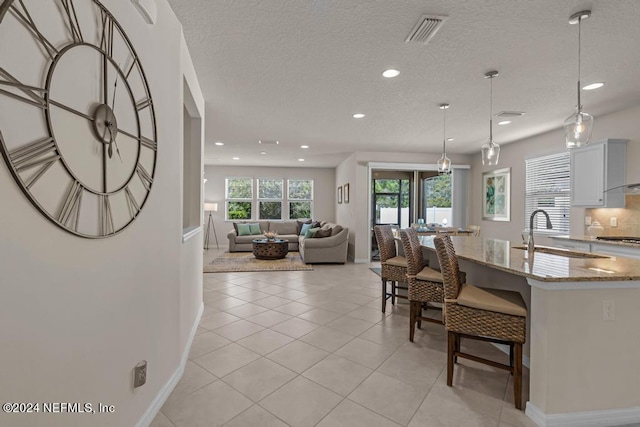 kitchen with sink, light stone countertops, tasteful backsplash, decorative light fixtures, and white cabinetry