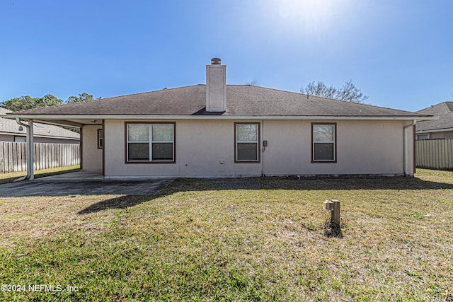 rear view of property with a yard and a carport