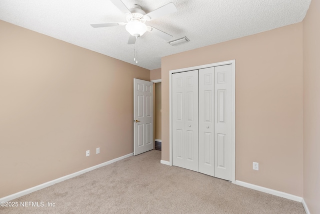 unfurnished bedroom with ceiling fan, light colored carpet, a textured ceiling, and a closet