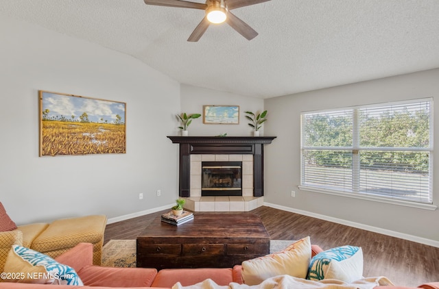 living room with a tile fireplace, wood-type flooring, and a textured ceiling