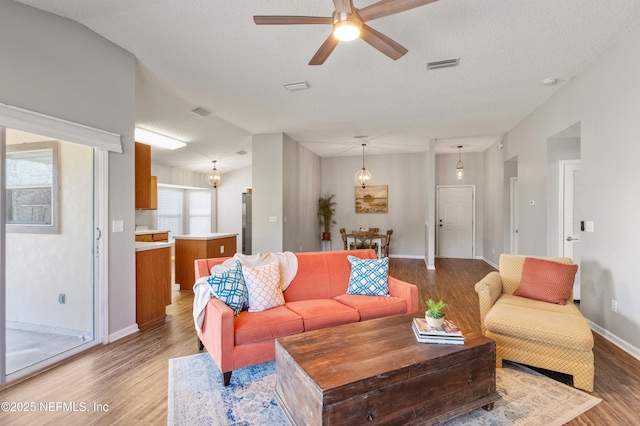 living room with a textured ceiling, hardwood / wood-style flooring, and ceiling fan