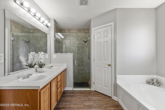 bathroom featuring separate shower and tub, vanity, wood-type flooring, and a textured ceiling