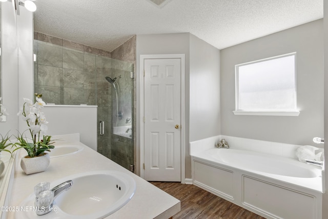 bathroom with vanity, wood-type flooring, a textured ceiling, and plus walk in shower