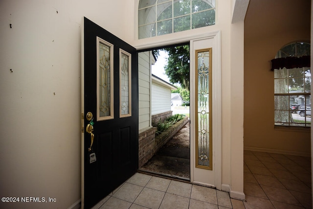 entryway with light tile patterned floors and a high ceiling