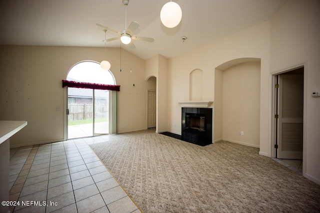 unfurnished living room featuring a tiled fireplace, light tile patterned floors, high vaulted ceiling, and ceiling fan