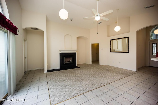 unfurnished living room with high vaulted ceiling, light colored carpet, and ceiling fan