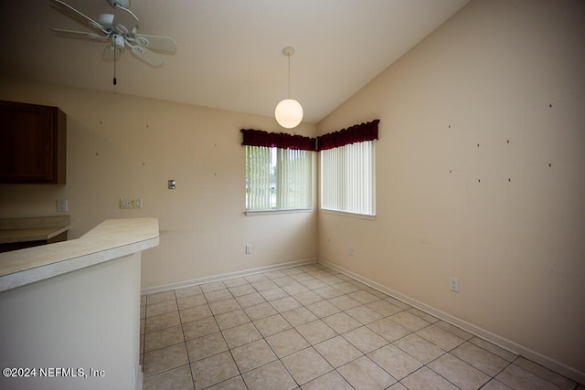 unfurnished dining area with ceiling fan, vaulted ceiling, and light tile patterned floors