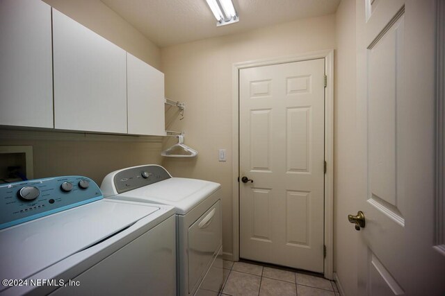 laundry area featuring cabinets, washer and dryer, and light tile patterned flooring