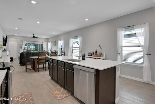 kitchen featuring ceiling fan, appliances with stainless steel finishes, sink, light hardwood / wood-style flooring, and a center island with sink